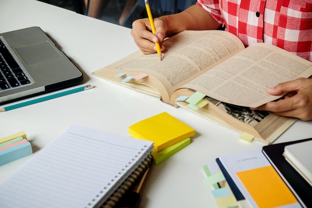 Writing workshop with notebook, sticky notes and research.